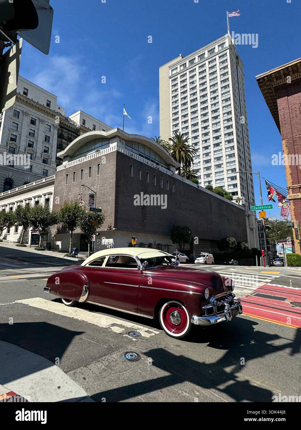 Auto d'epoca d'epoca d'epoca che passa davanti al Fairmont Hotel a Nob Hill, San Francisco, sotto il cielo azzurro. - Immagine stock catturata con smartphone