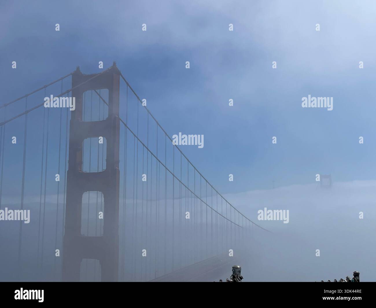Golden Gate Bridge che emerge dalla nebbia costiera sulla baia di San Francisco sotto un cielo azzurro e limpido, creando una scena di viaggio suggestiva e iconica. - Immagine stock catturata con smartphone