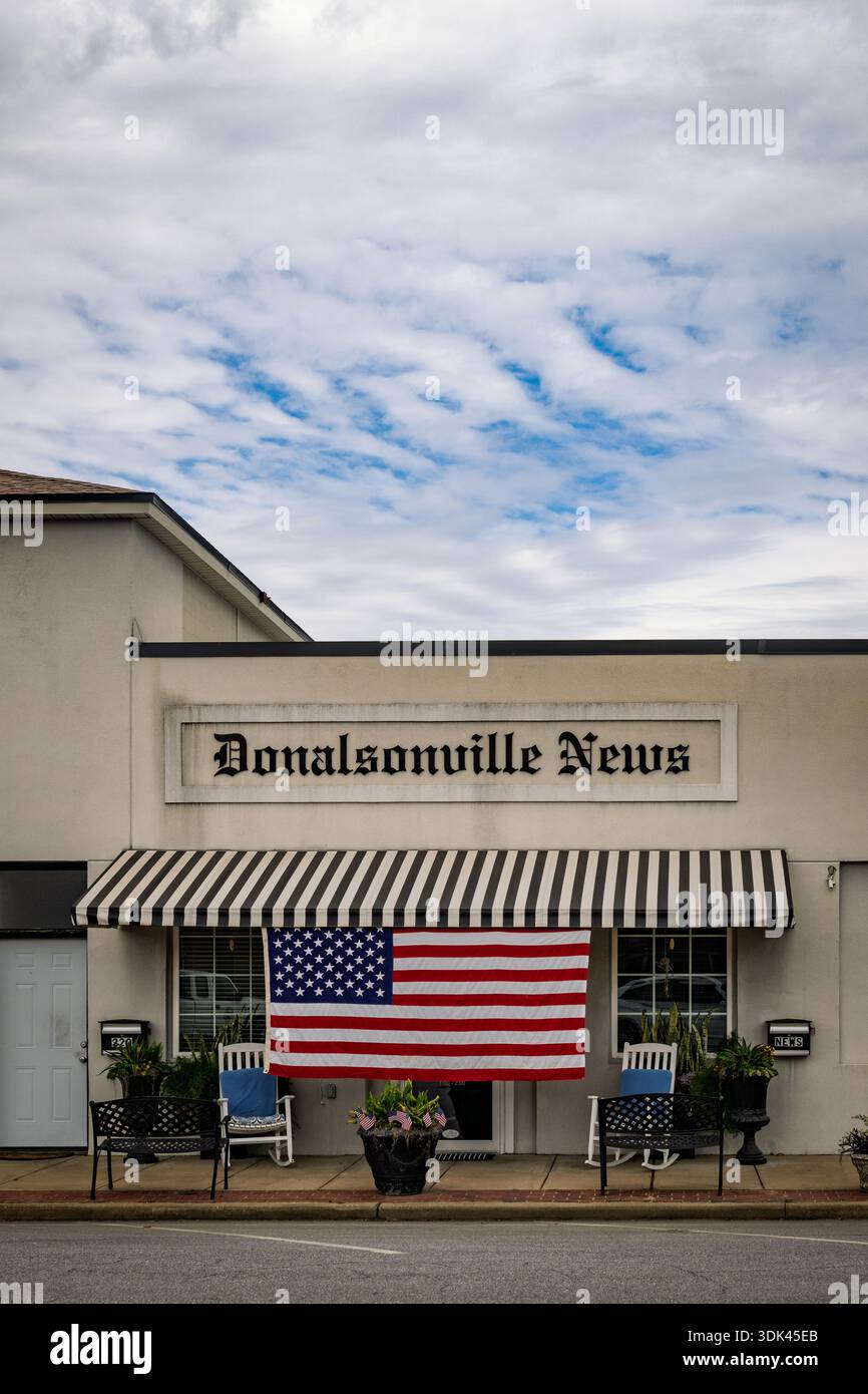 Sotto un cielo pesante e nuvoloso, l'edificio di Donalsonville News si erge a guardia di una strada tranquilla nella Georgia rurale. Una grande bandiera americana è impiccata immobile, Foto Stock