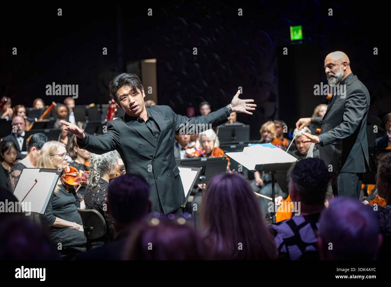 Cantante maschile in giacca di velluto nero che riceve una standing ovation e applausi dopo un concerto dal vivo dell'AIMS Festival Orchestra a Graz. Foto Stock