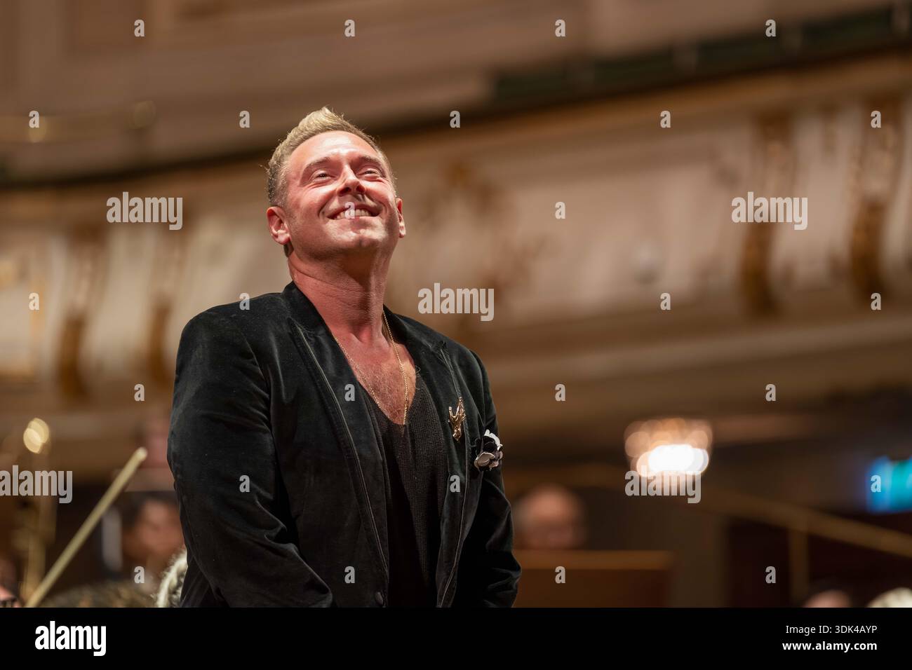 Cantante maschile in giacca di velluto nero che riceve una standing ovation e applausi dopo un concerto dal vivo. Foto Stock
