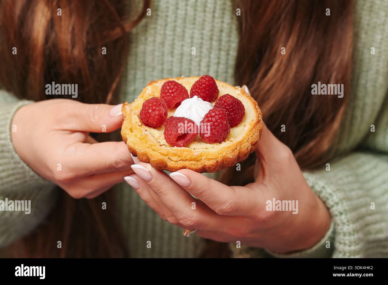 Tartlet di lamponi tenuto in primo piano. Dessert di frutta fresca con ripieno di panna. Pasticcini fatti in casa serviti per momenti dolci. Foto Stock