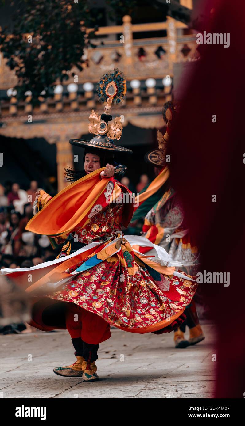 Posa dinamica di una ballerina bhutanese in costume rosso e cappello decorato Foto Stock