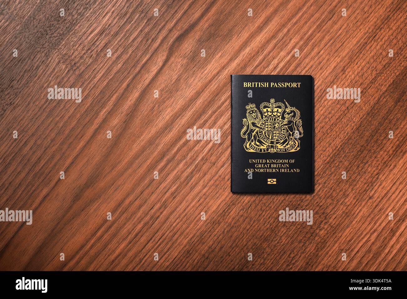 Un unico passaporto britannico giace su una superficie di legno neutra. La copertina presenta testo in rilievo e l'emblema nazionale. L'immagine evidenzia il tr ufficiale Foto Stock