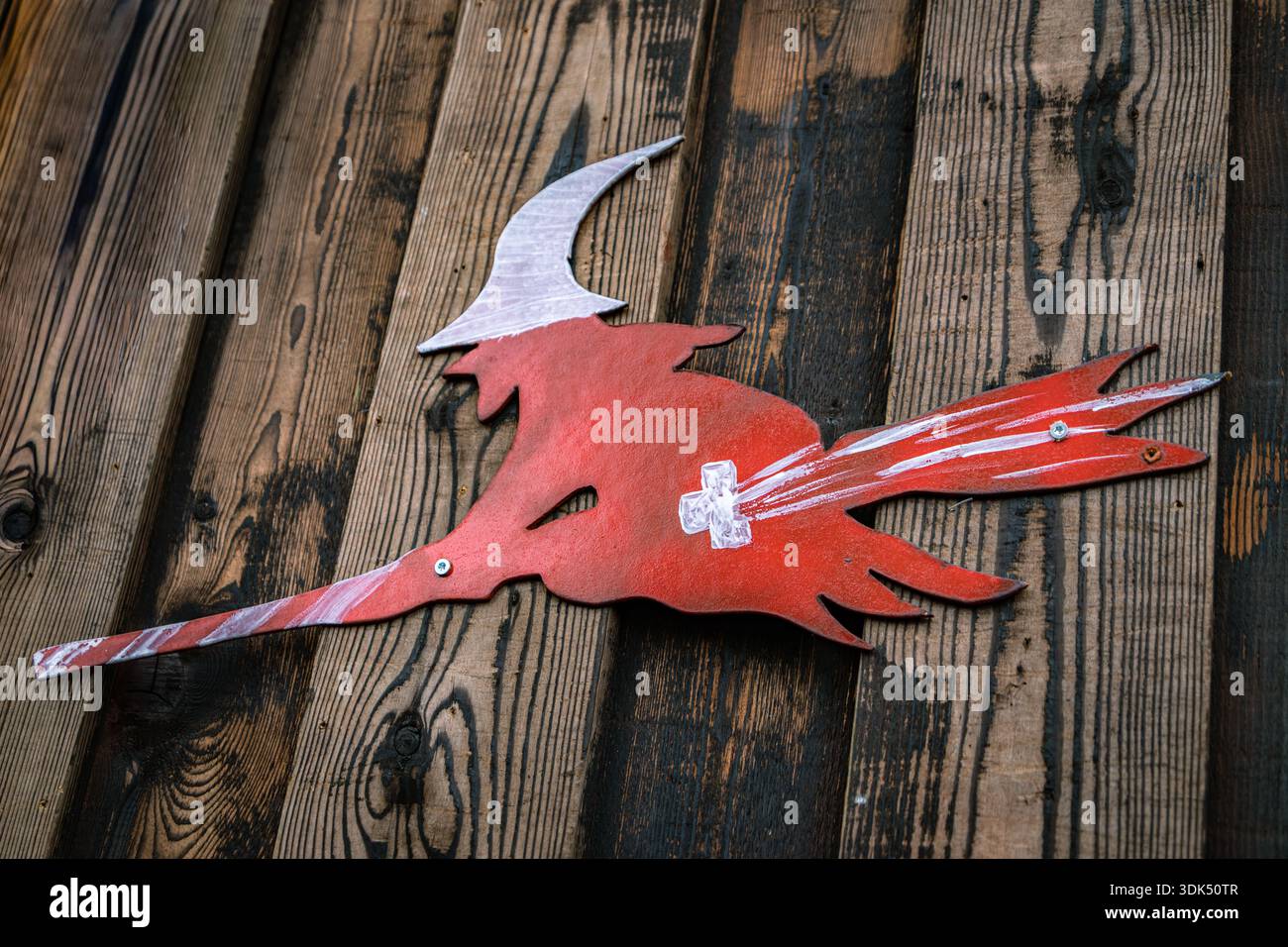 Silhouette rossa di una strega volante su una scopa con il simbolo della bandiera svizzera su una parete di legno per la sfilata di Carnevale invernale di Fasnacht a Zugo, Svizzera Foto Stock