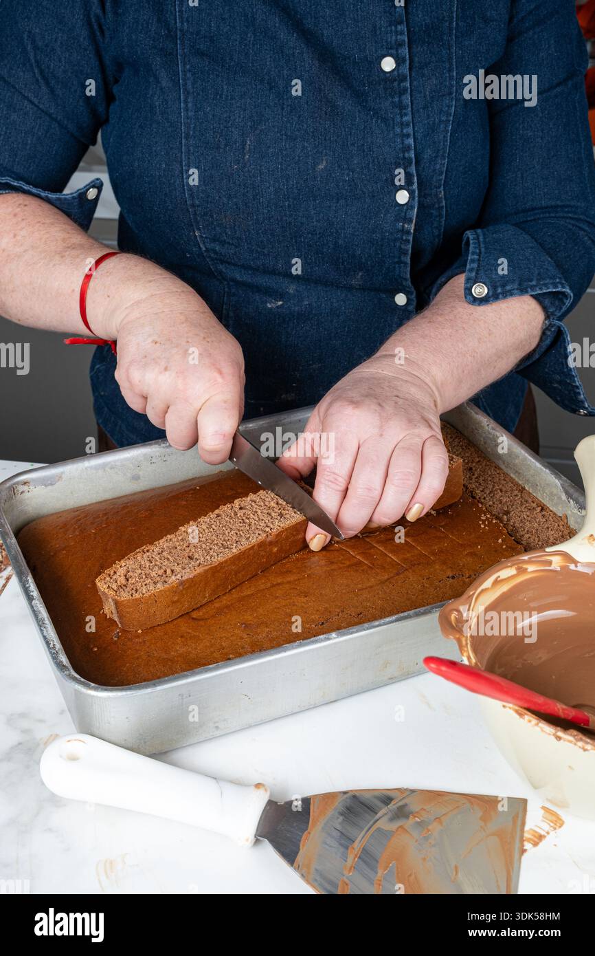 Un dolcificante tagliando la torta brasiliana al miele a pezzi verticali. Foto Stock