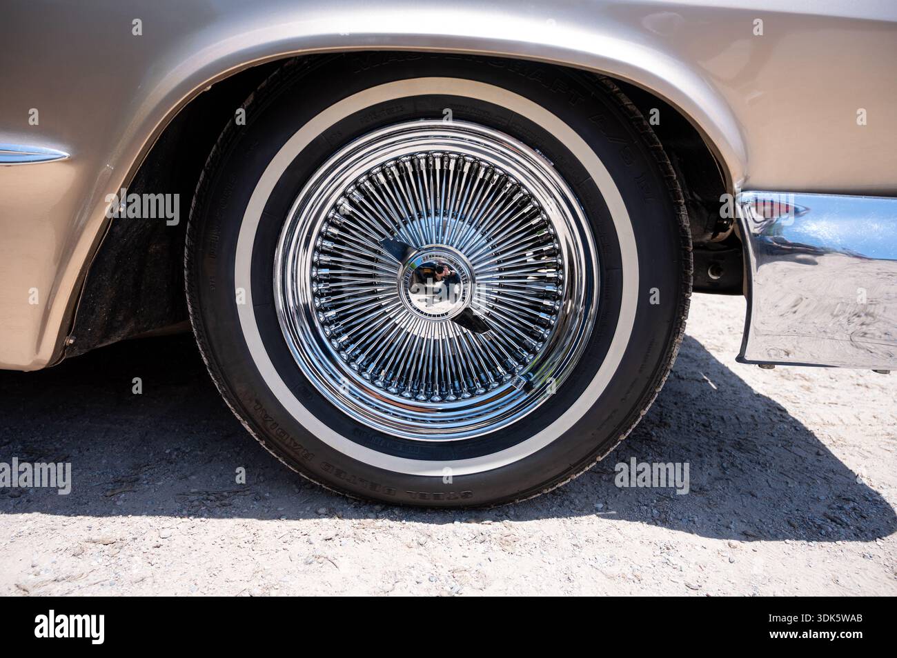Primo piano dettagliato di una ruota in filo cromato a più razze con un mozzo rimovibile su una classica Chevrolet Impala, che mette in risalto la sua finitura lucida e la Foto Stock