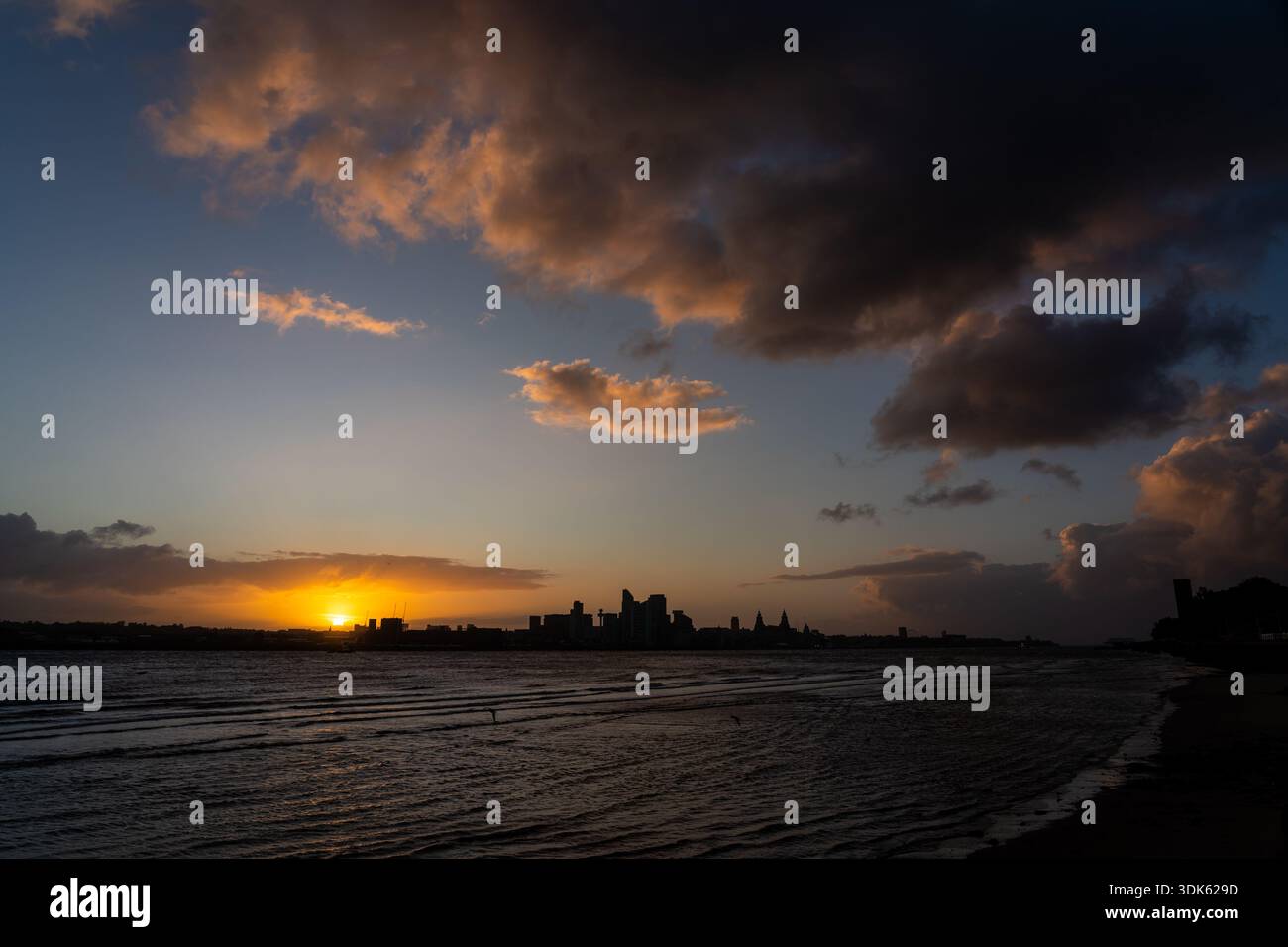 Vista panoramica mattutina della città di Liverpool che si staglia sull'acqua ondulata del fiume mentre il sole attraversa un cielo suggestivo Foto Stock