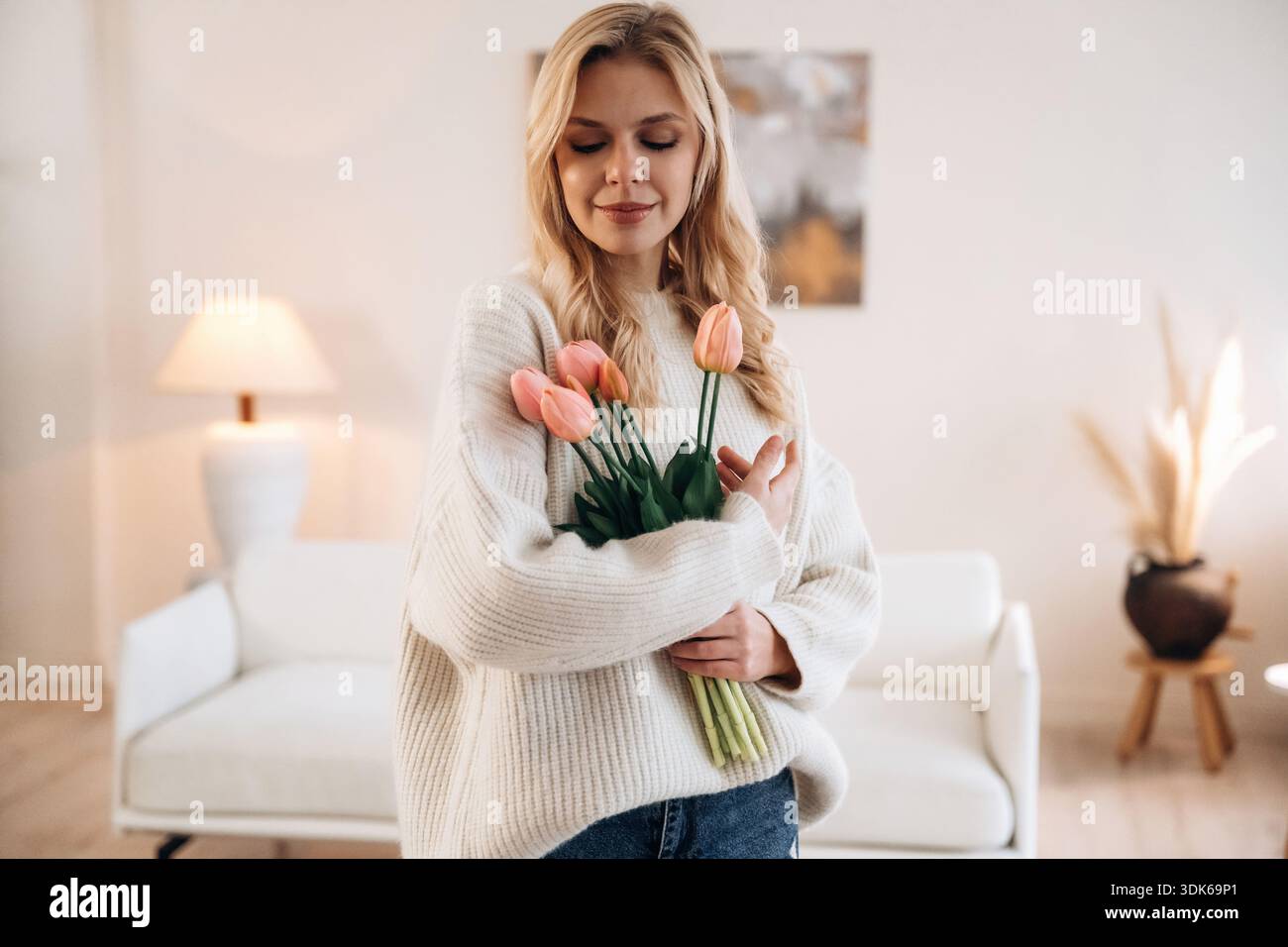 Felice espressione facciale. La bella giovane donna è a casa con i fiori. Foto Stock
