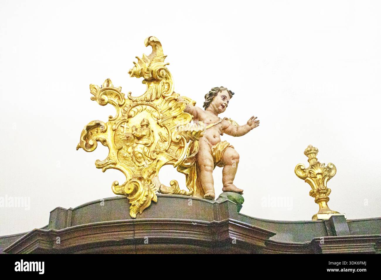 Cornice decorativa dorata in stile barocco o rococò con una statua di Cupido su sfondo chiaro Foto Stock