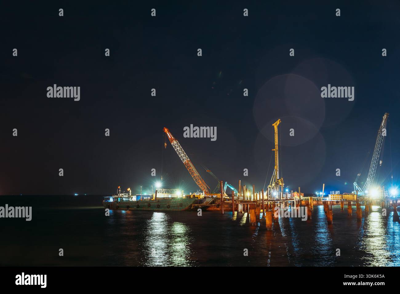 Gru e chiatte da costruzione che lavorano in mare di notte a Phu Quoc Foto Stock