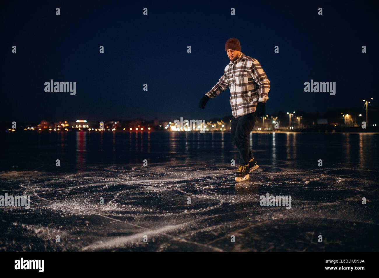 Sera. Un uomo è sul ghiaccio con i suoi pattini in inverno. Foto Stock