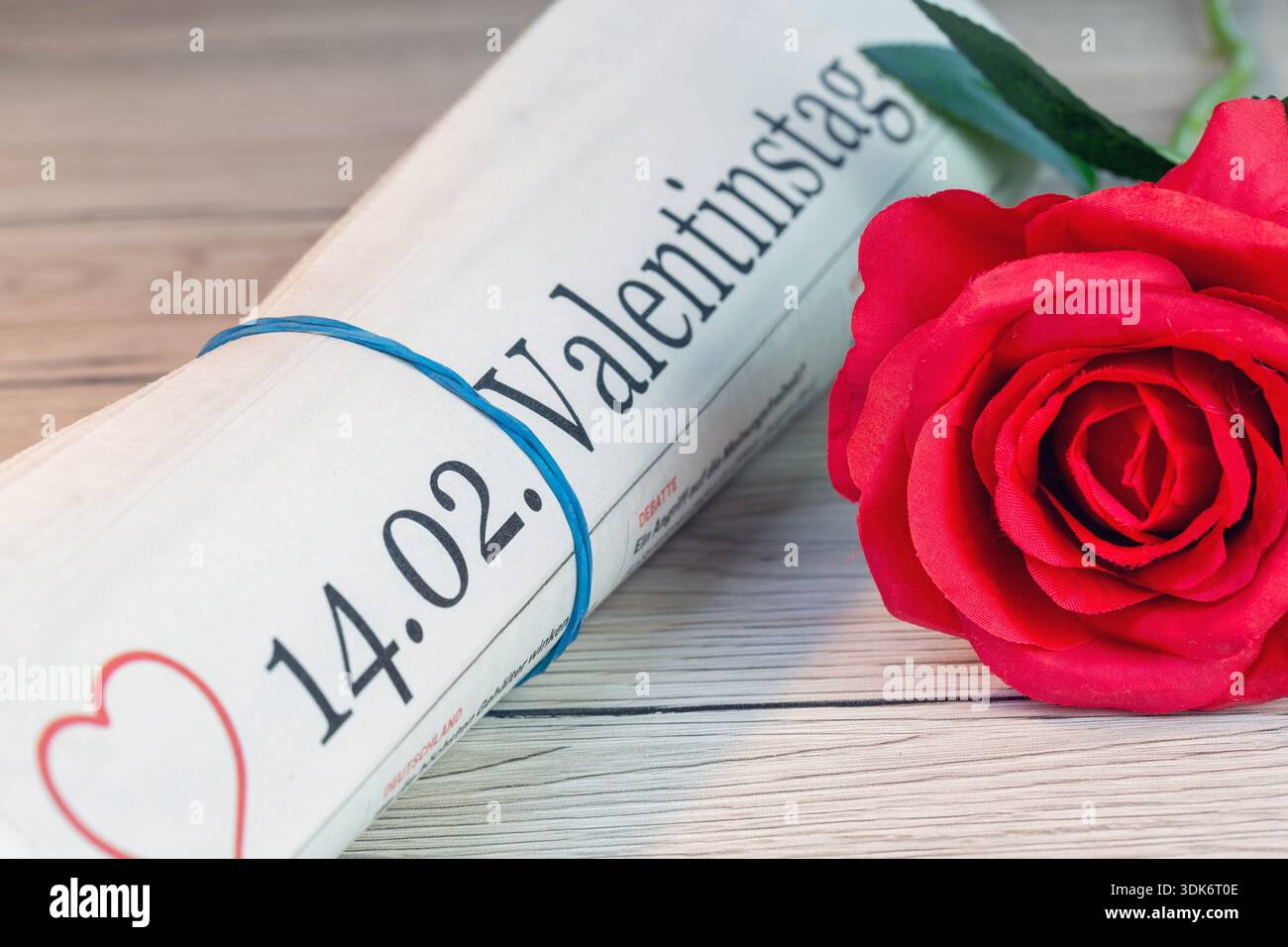 Giornale simbolico con il titolo 14.02. VALENTINSTAG accanto a una rosa rossa Foto Stock