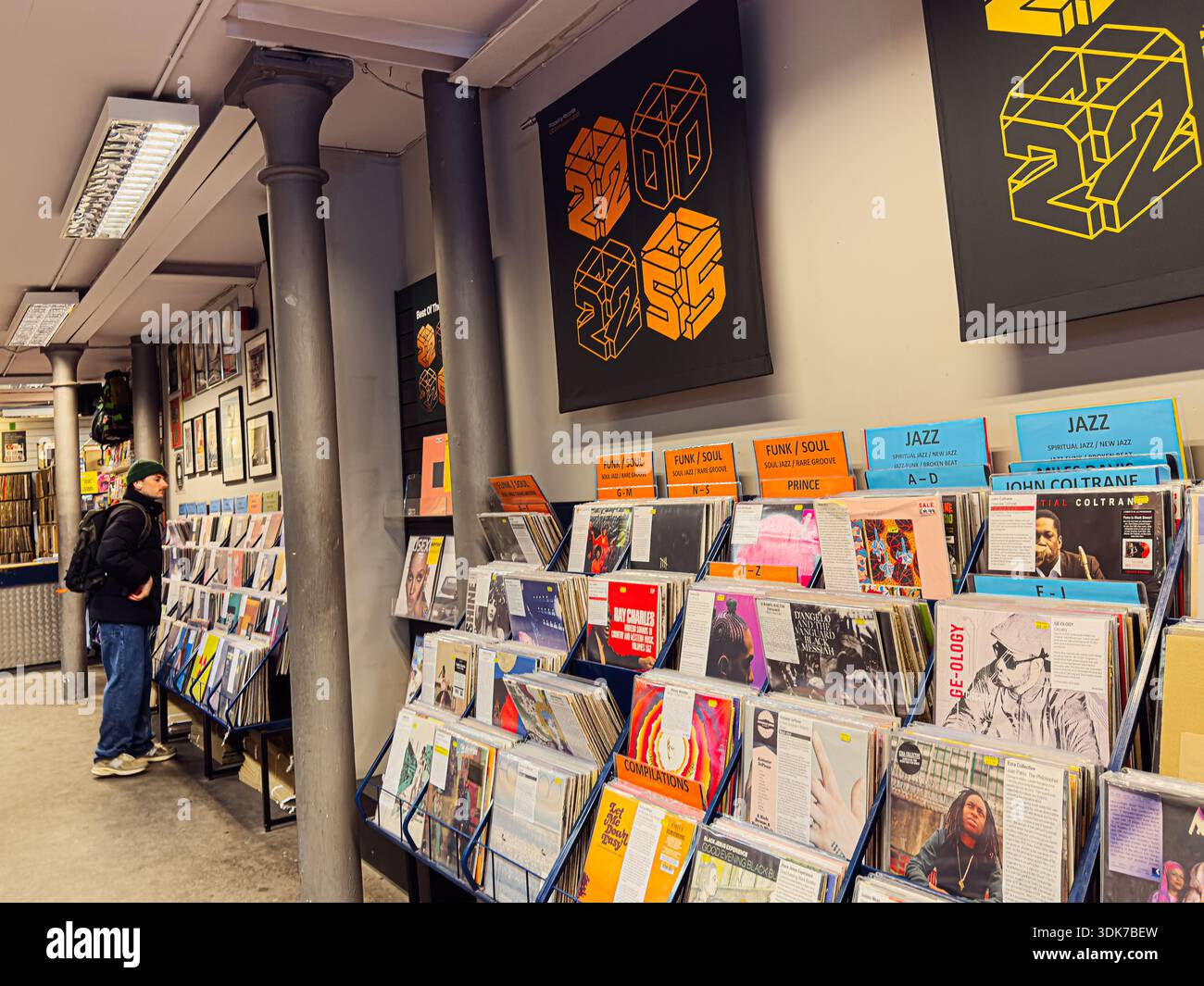 Manchester, Regno Unito - 21 gennaio 2026: Gli acquirenti occasionali sfogliano i dischi in vinile in un moderno negozio di dischi pieno di poster colorati e scaffali espositivi. Foto Stock