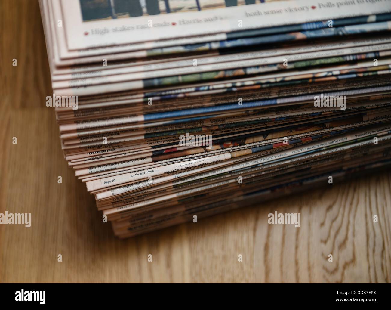 Vista ravvicinata di giornali impilati appoggiati su una superficie di legno che mostra pagine stratificate titoli e texture di stampa che simboleggiano le informazioni sul giornalismo dei media di notizie Foto Stock
