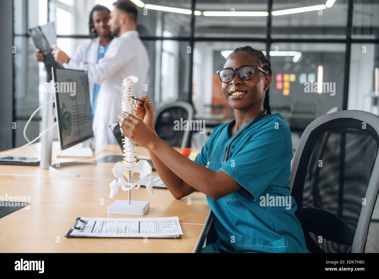 Concezione educativa, che mostra il modello umano della colonna vertebrale. I medici lavorano in ufficio. Foto Stock