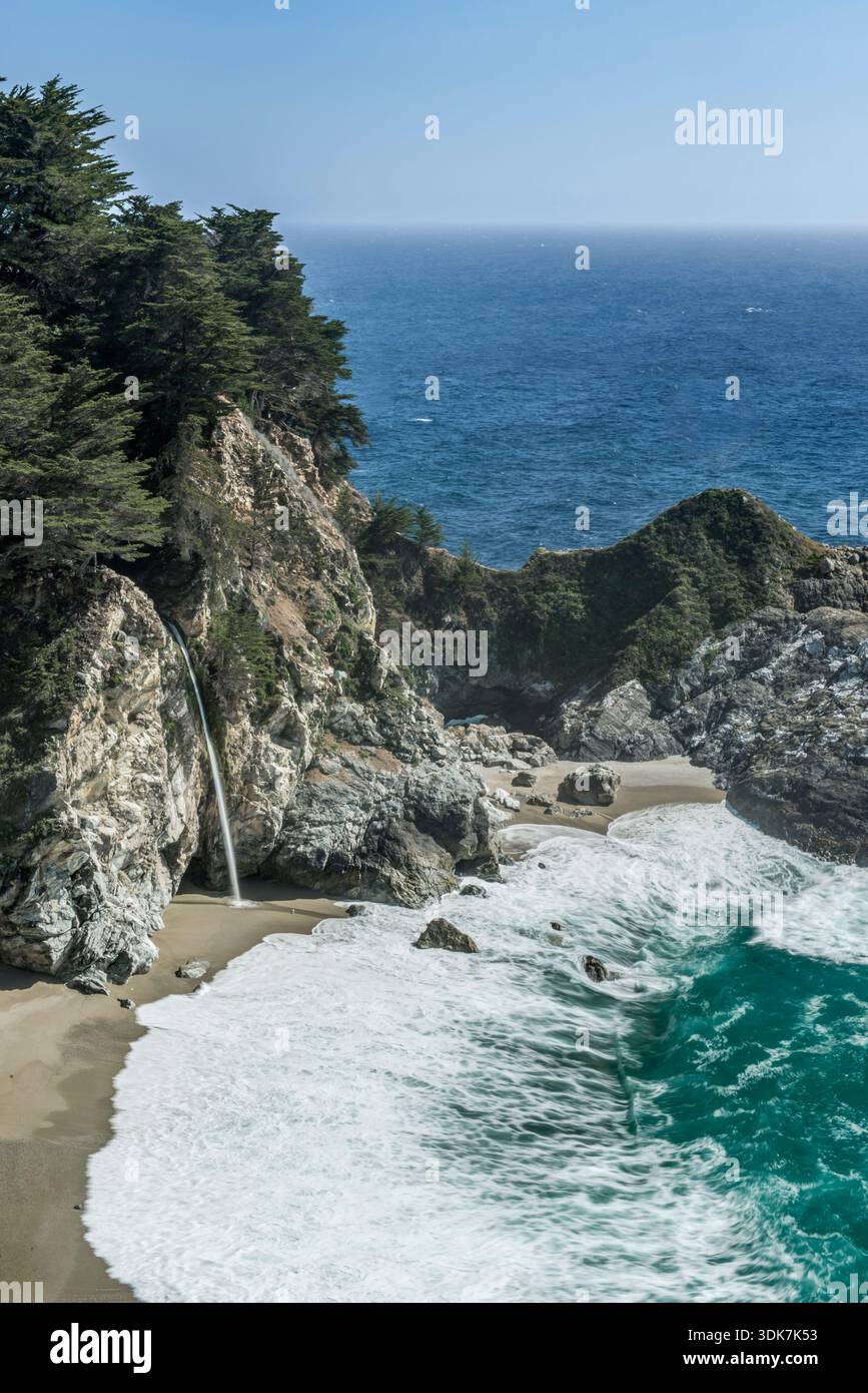 Parco statale Julia Pfeiffer Burns, vista elevata sulla spiaggia, onde che si infrangono, scogliere ripide e una cascata. Foto Stock