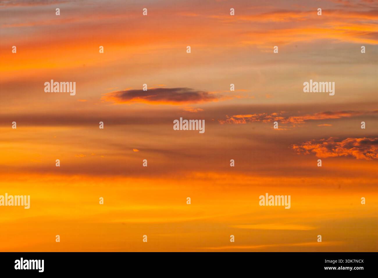 Vista di un tramonto ardente che dipinge il cielo con arance e gialli vibranti, nuvole striate con sfumature di viola e grigio, Lahore, Punjab, Pakistan. Foto Stock