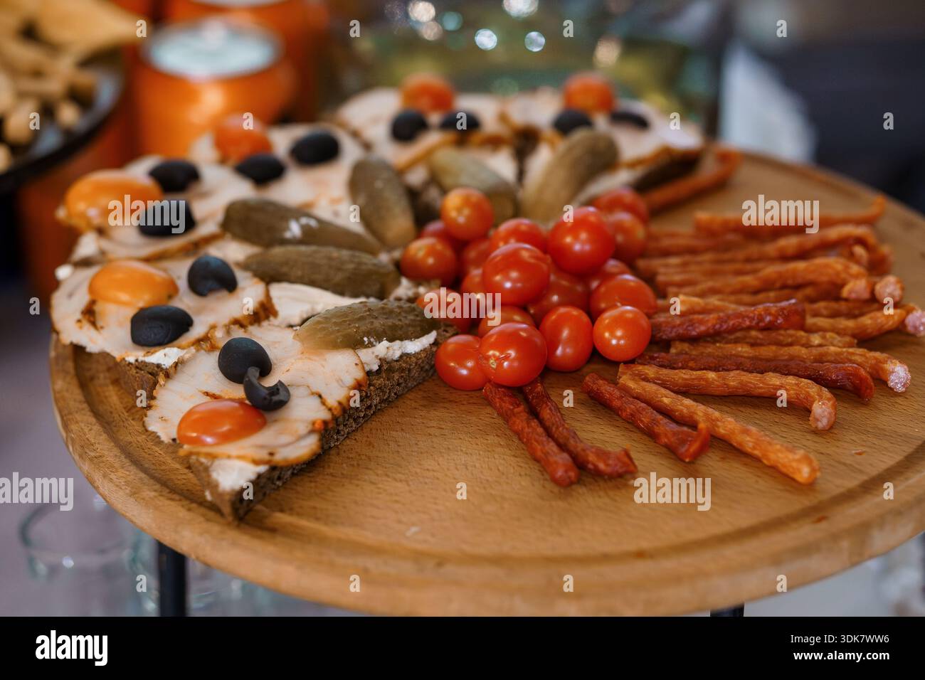 Vassoio di antipasti assortiti con toast al salmone affumicato, sottaceti, olive, pomodori ciliegini e salsicce su un tavolo da portata in legno Foto Stock