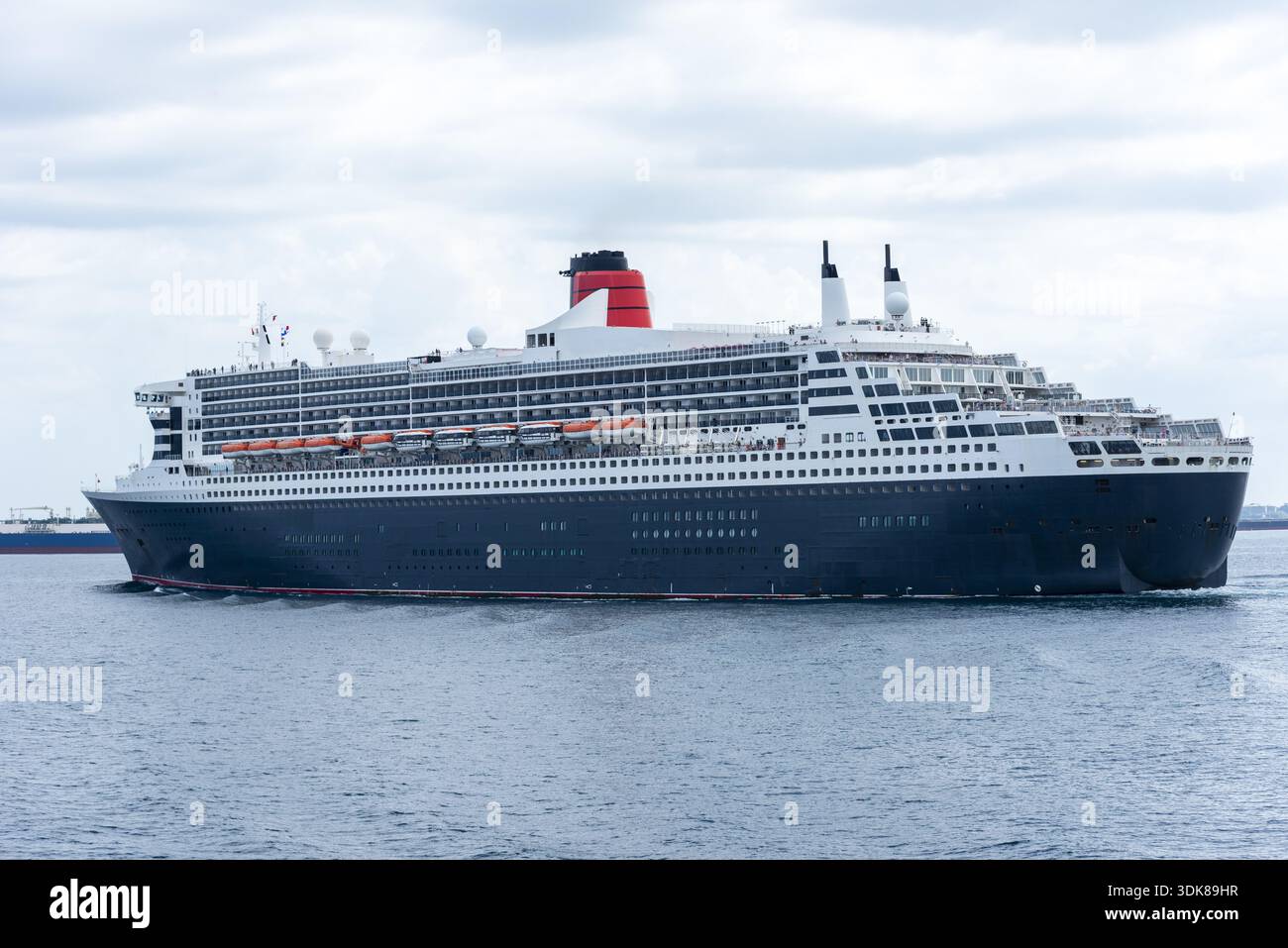 Grande nave da crociera di lusso che naviga attraverso l'Oceano Pacifico, con vista laterale completa sotto un cielo leggermente nuvoloso. Foto Stock