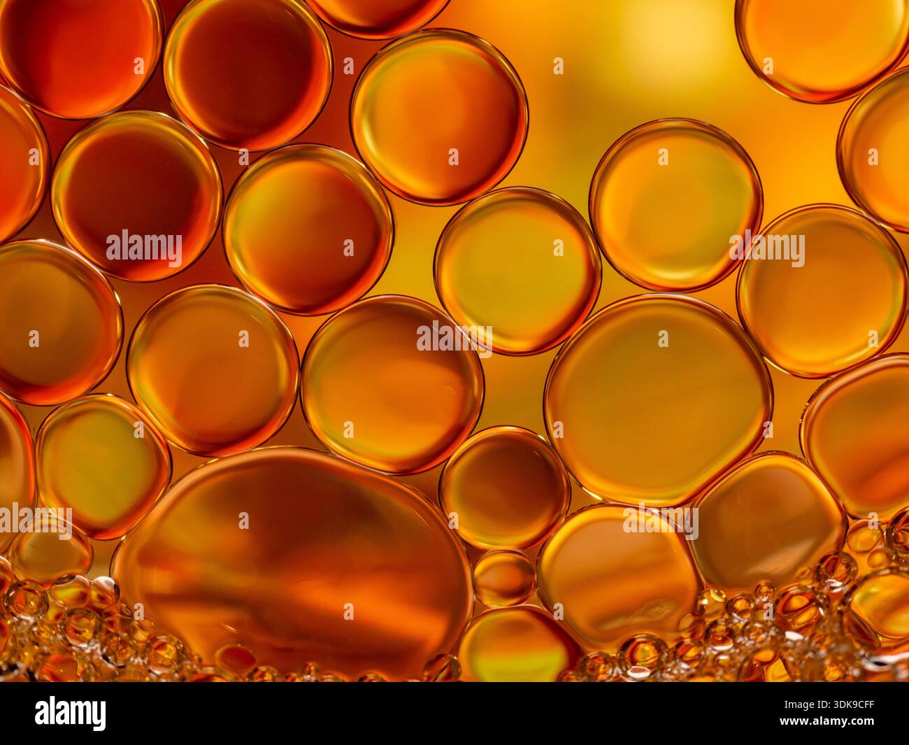 Un primo piano di bolle d'olio dorate in una tavolozza arancione calda, con forme rotonde, superfici lisce e profondità traslucida. Perfetto per backg astratto Foto Stock
