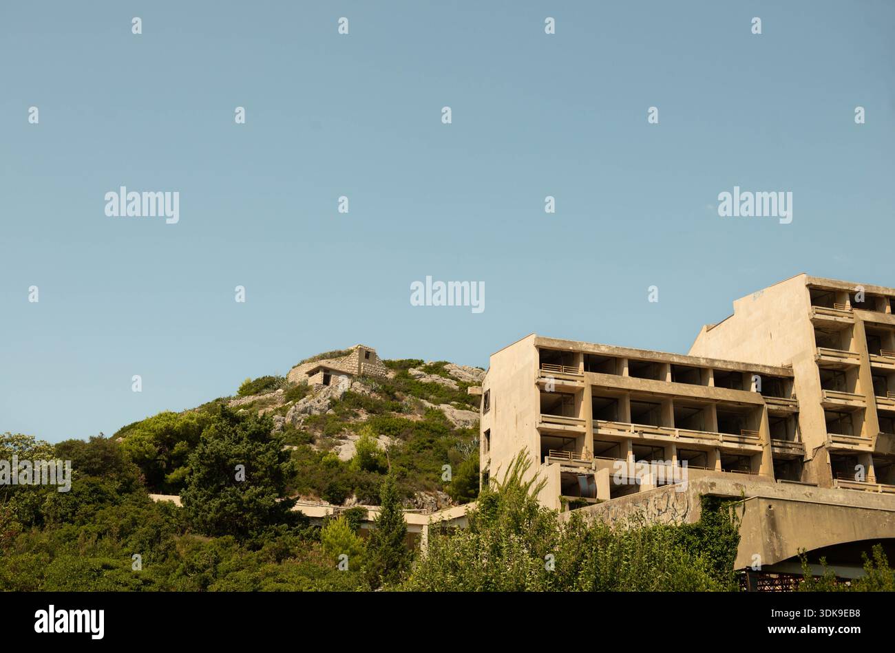 KUPARI, CROAZIA - 29 LUGLIO 2024: Hotel brutalista rovinato con un bunker militare sulla collina sopra. Distrusse blocchi di cemento dalla guerra degli anni '1990 Foto Stock