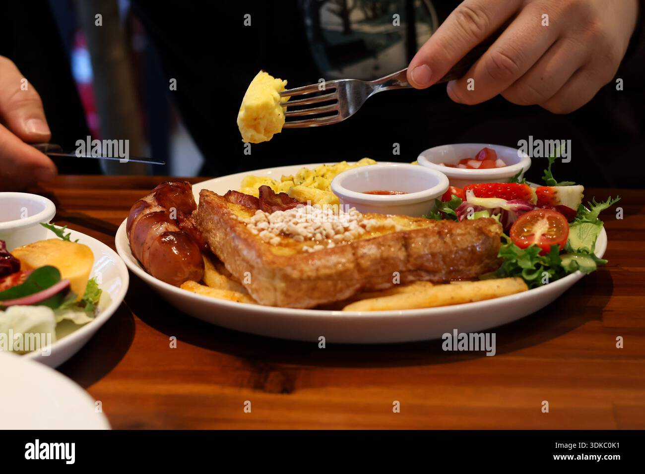 Colazione tradizionale con uova strapazzate, pane tostato e salsiccia su un tavolo di legno Foto Stock