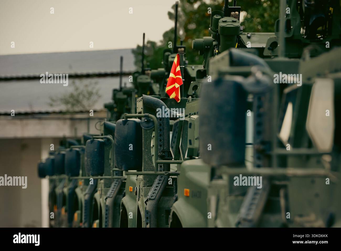 Bandiera della Macedonia esposta su una fila di veicoli tattici militari corazzati parcheggiati in una struttura militare Foto Stock