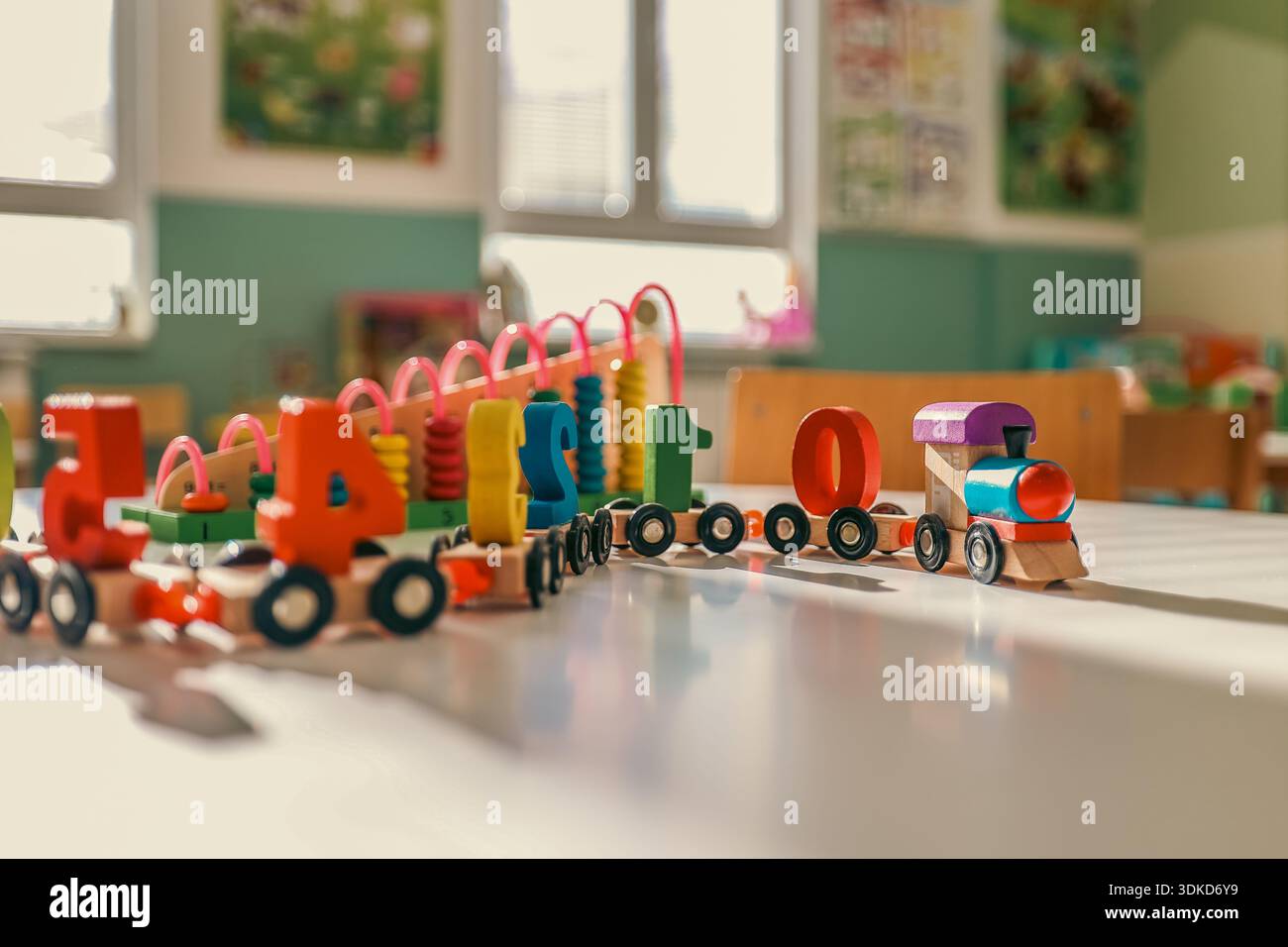 Giocattoli educativi in legno colorati disposti su un tavolo all'interno di un asilo o di un'aula prescolare Foto Stock