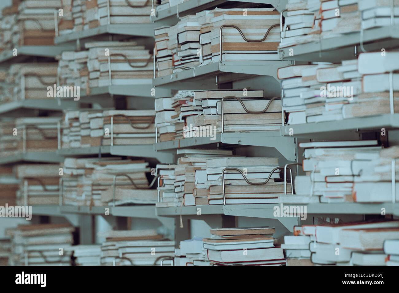 Pile di vecchi libri e documenti conservati su scaffali metallici all'interno di un archivio libreria Foto Stock