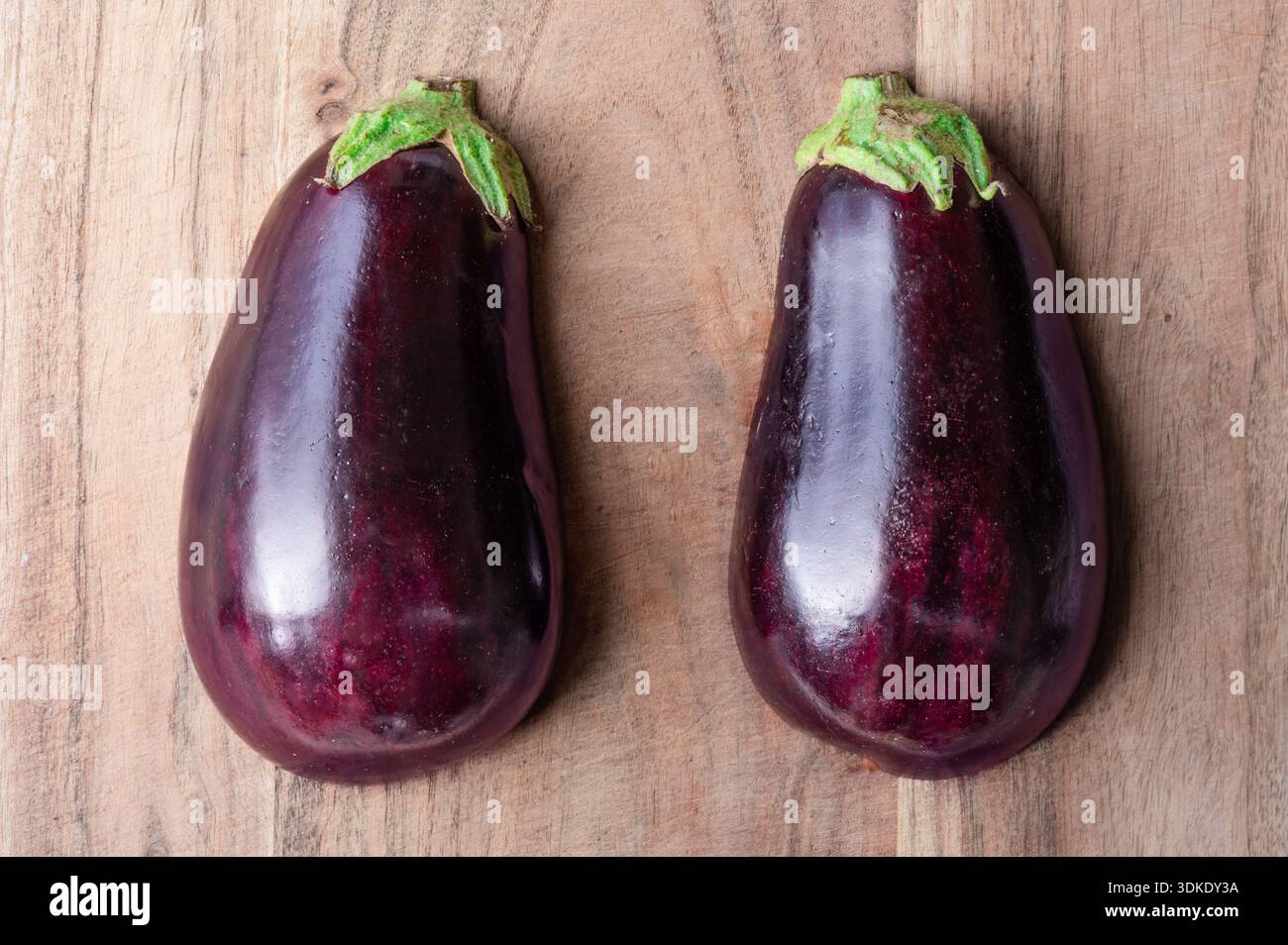 L'esterno di una melanzana tagliata a metà, due metà su un tagliere di legno Foto Stock