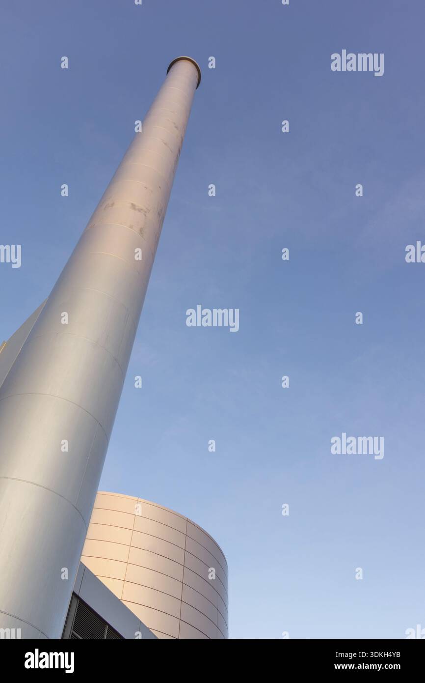 Frederiksund, Danimarca, 6 gennaio 2017 - cisterna petrolifera e camino in una centrale termica. Un chimneypot alto contro il cielo blu Foto Stock