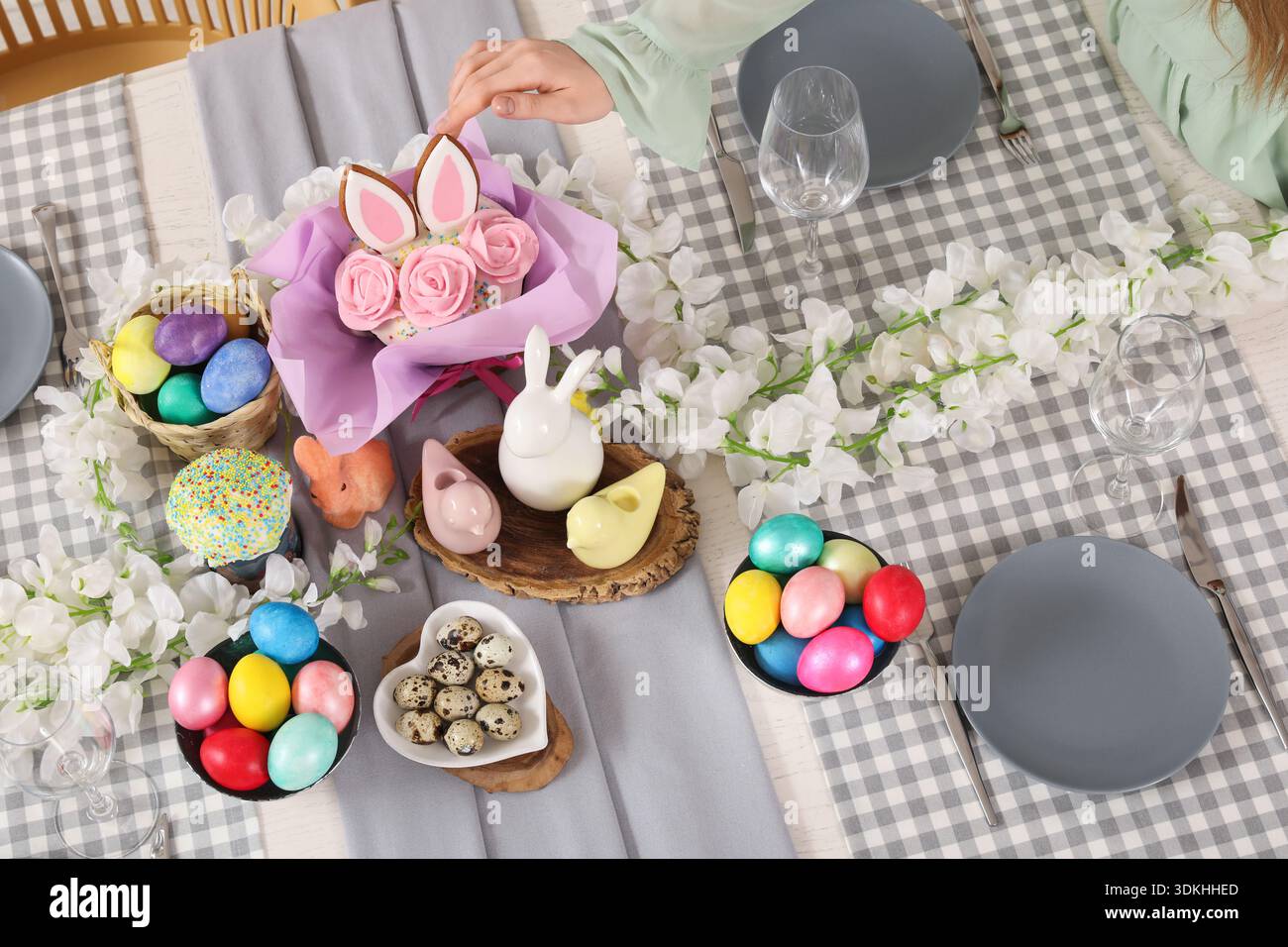 Mano femminile che tocca la torta pasquale sul tavolo delle feste Foto Stock
