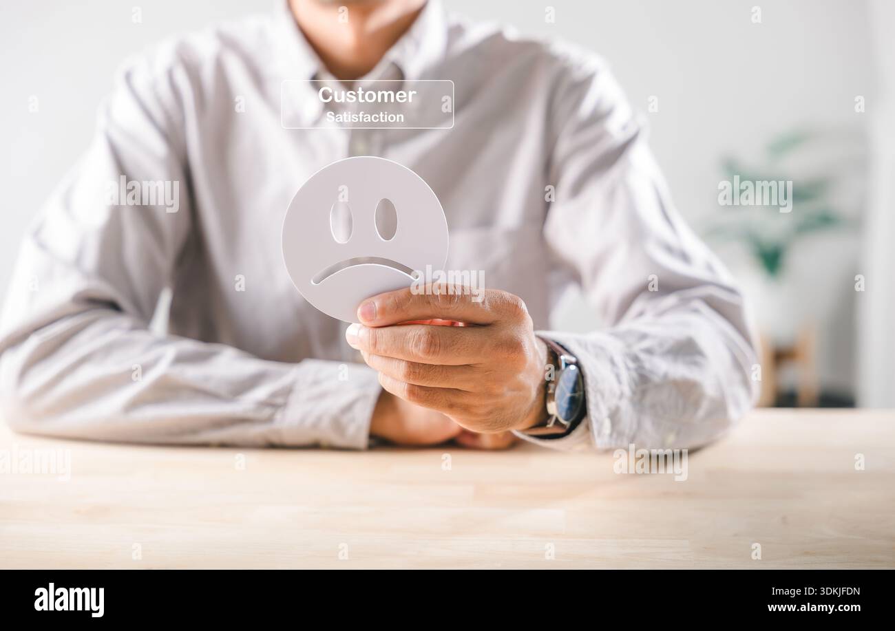 Il feedback negativo del cliente è chiaramente indicato come icona con la mano che tiene in mano il volto triste, che suggerisce un servizio scadente, un'esperienza infelice, una valutazione scadente e una scarsa soddisfazione sc Foto Stock