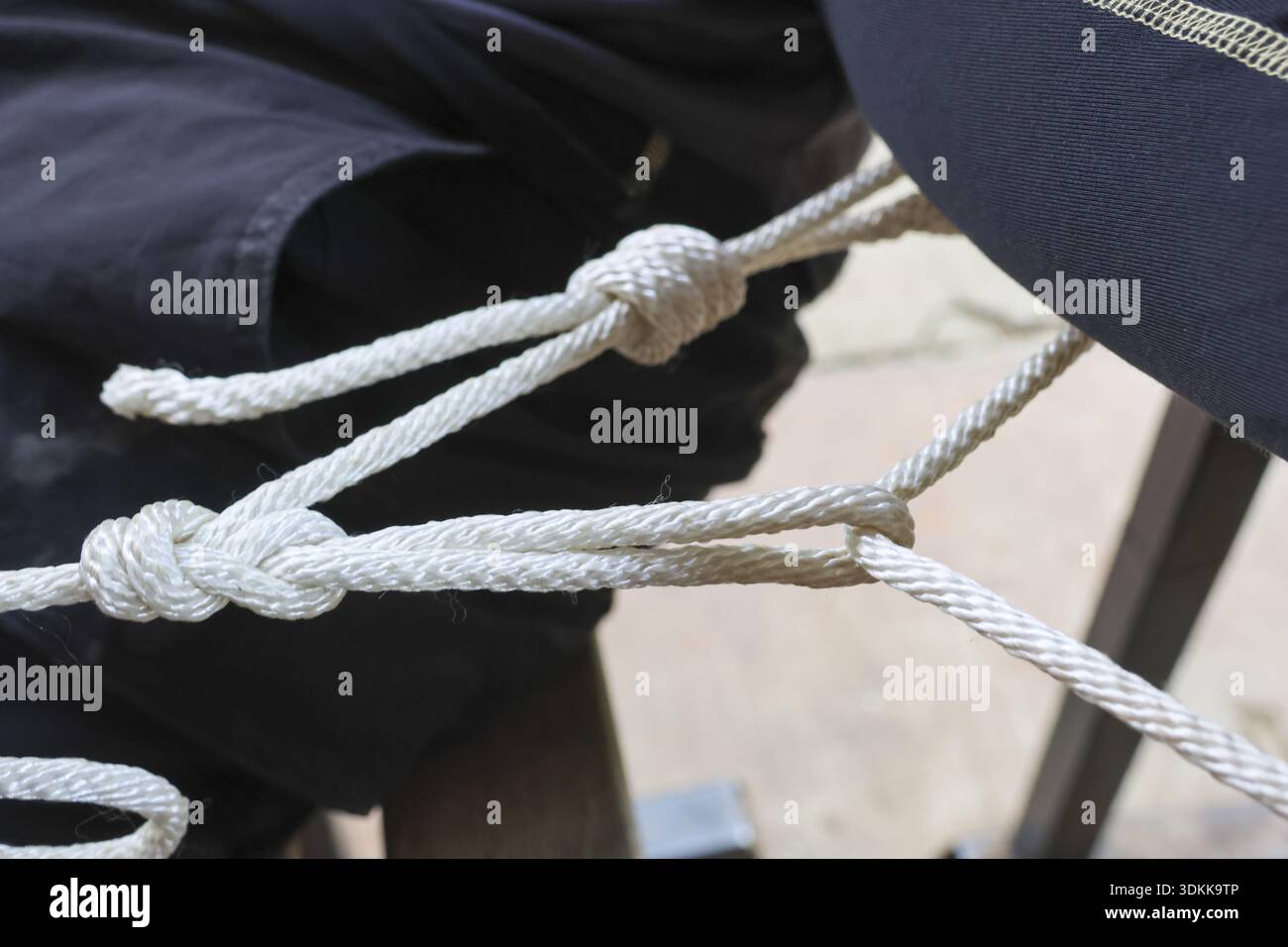 Primo piano forte di corda bianca con nodo sicuro. fascetta di fissaggio che mostra un saldo collegamento del filo unito, che rappresenta il legame, la resistenza e l'affidabilità Foto Stock