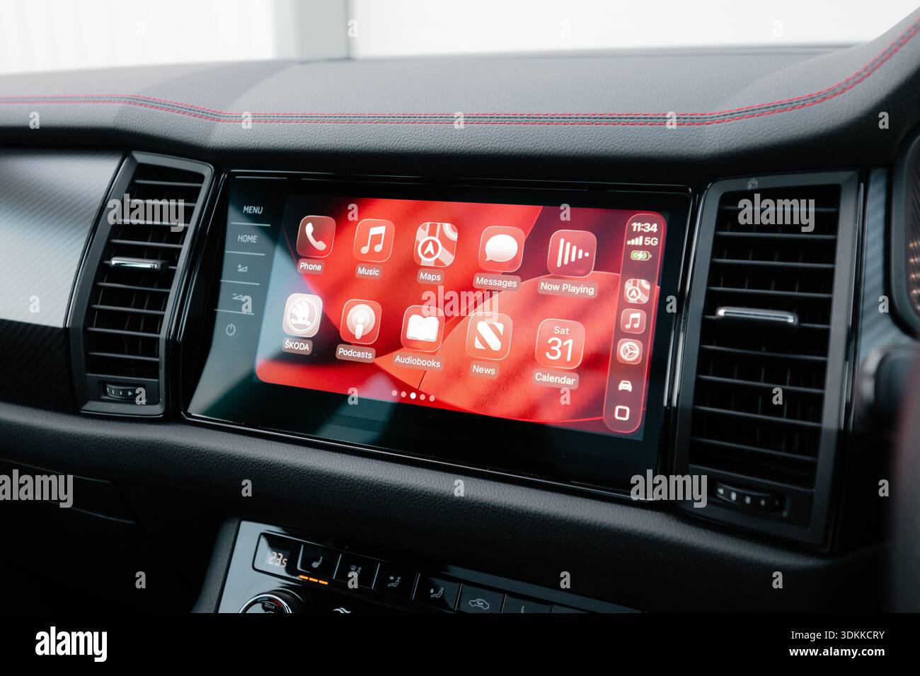 Primo piano del sistema di informazione e intrattenimento Apple CarPlay visualizzato su un moderno cruscotto dell'auto che mostra la musica e i messaggi di navigazione per consentire la guida connessa Foto Stock
