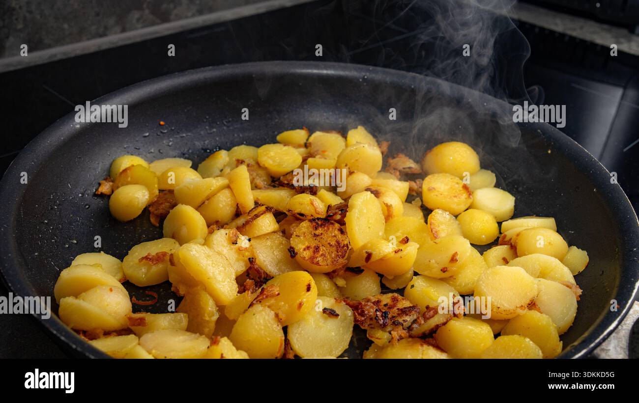 Deliziose patate fritte croccanti con cipolle dorate, cucinate alla perfezione in una padella calda, che presenta un cibo confortevole sfrigolante, saporito e fatto in casa Foto Stock