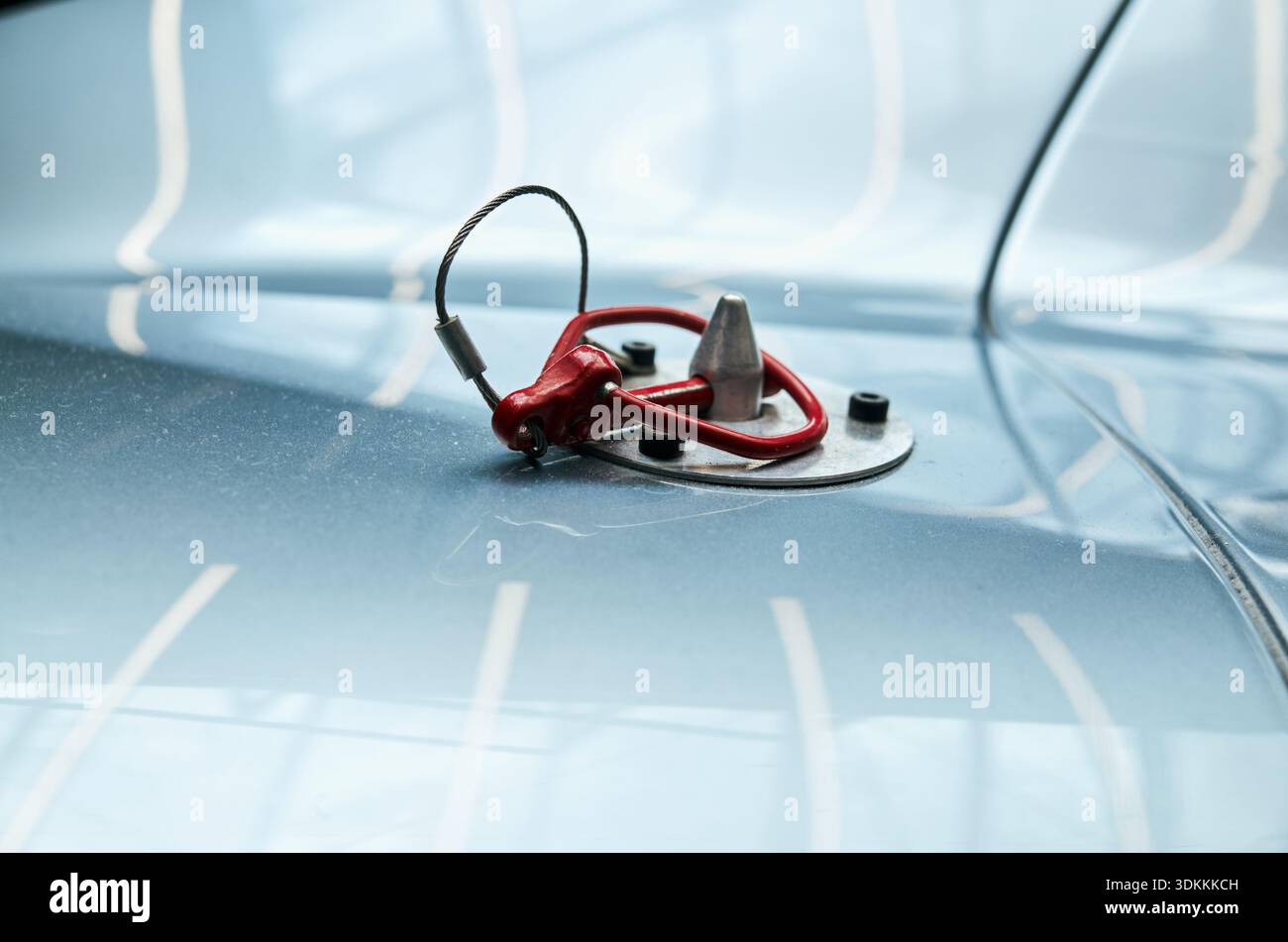 Primo piano del tappo del carburante vintage sul cofano, vernice blu pallido lucido che riflette la luce da studio, chiusura cromata con rosso Foto Stock