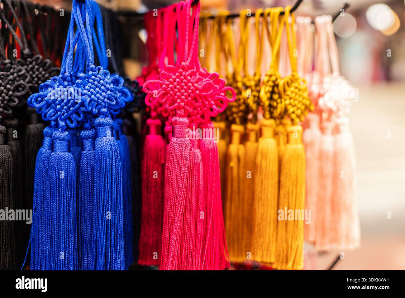 Le nappine luminose in vari colori sono esposte in un mercato. Gli acquirenti osservano le vivaci decorazioni che possono essere utilizzate per l'artigianato o gli accessori. Foto Stock