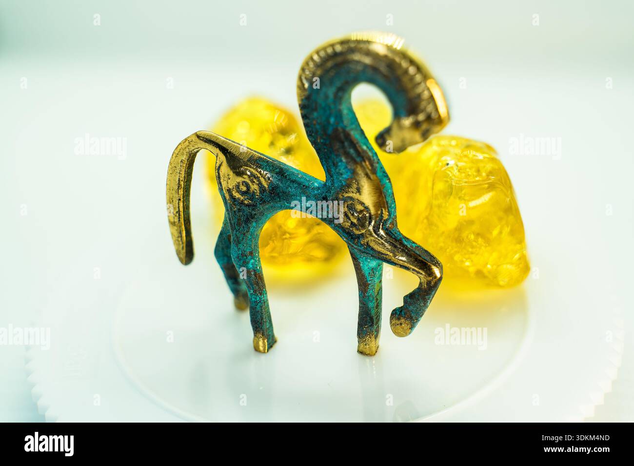 Una statuetta di cavallo dorata e blu si trova su un piatto bianco con due teschi gialli. Concetto di mistero e intrigo, come il cavallo e i teschi non sono comunemente Foto Stock