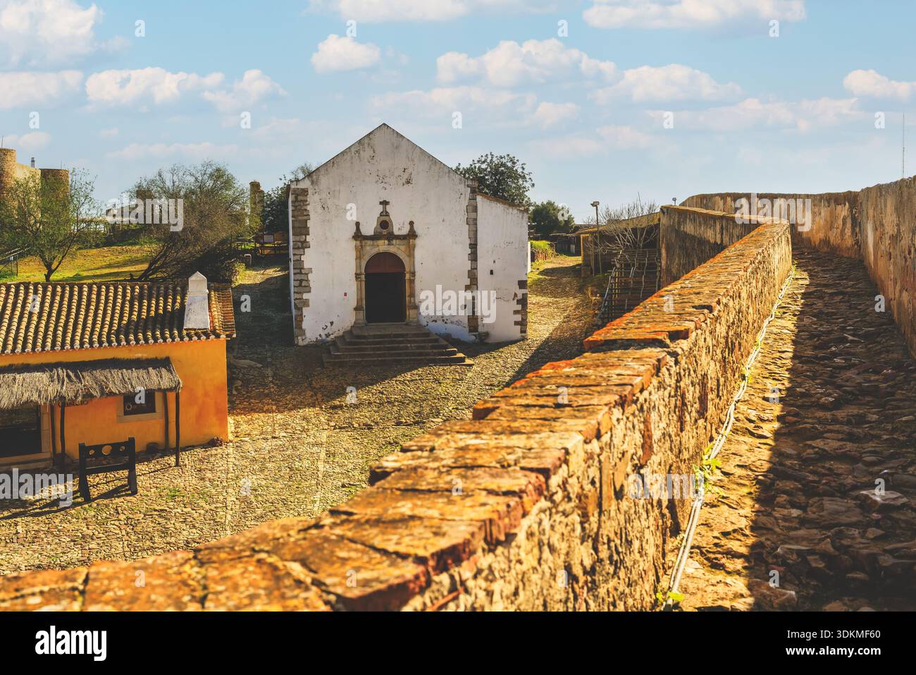 Il muro del castello di Castro Marims conduce a una piccola cappella bianca all'interno dei terreni della fortezza. Foto Stock