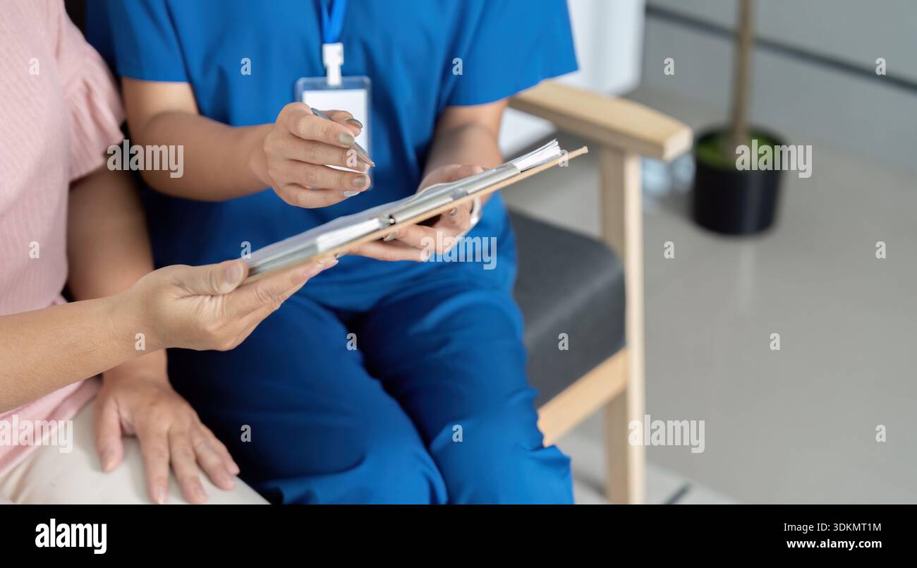 Una donna in uniforme blu è seduta su una sedia con un appunti di fronte a lei Foto Stock