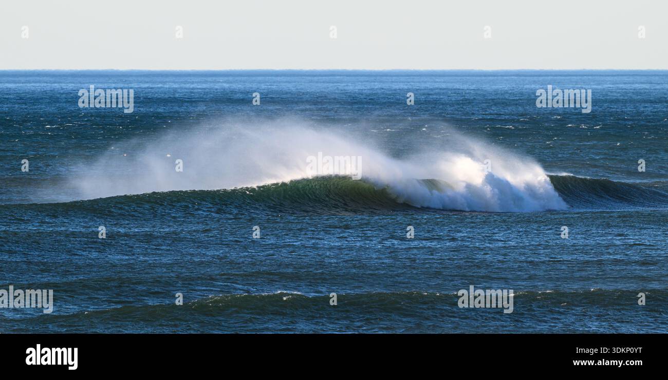 Onda oceanica soffiata dal forte vento che allontanava spruzzi dalla cresta verso l'orizzonte in nube di nebbia bianca Foto Stock