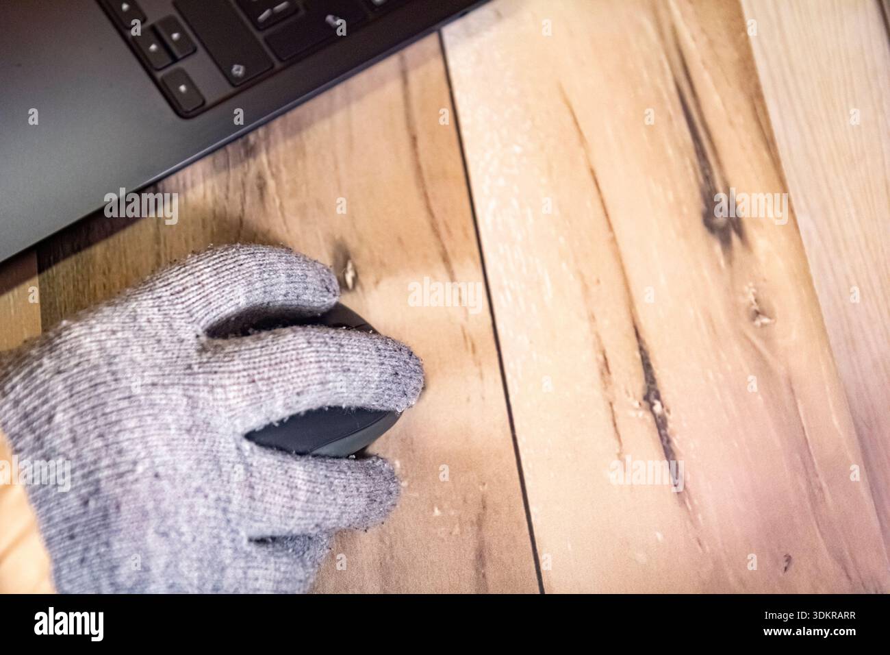 Vista dall'alto di una mano indossata con i guanti sul mouse del computer durante l'interruzione di corrente invernale, copia spazio Foto Stock