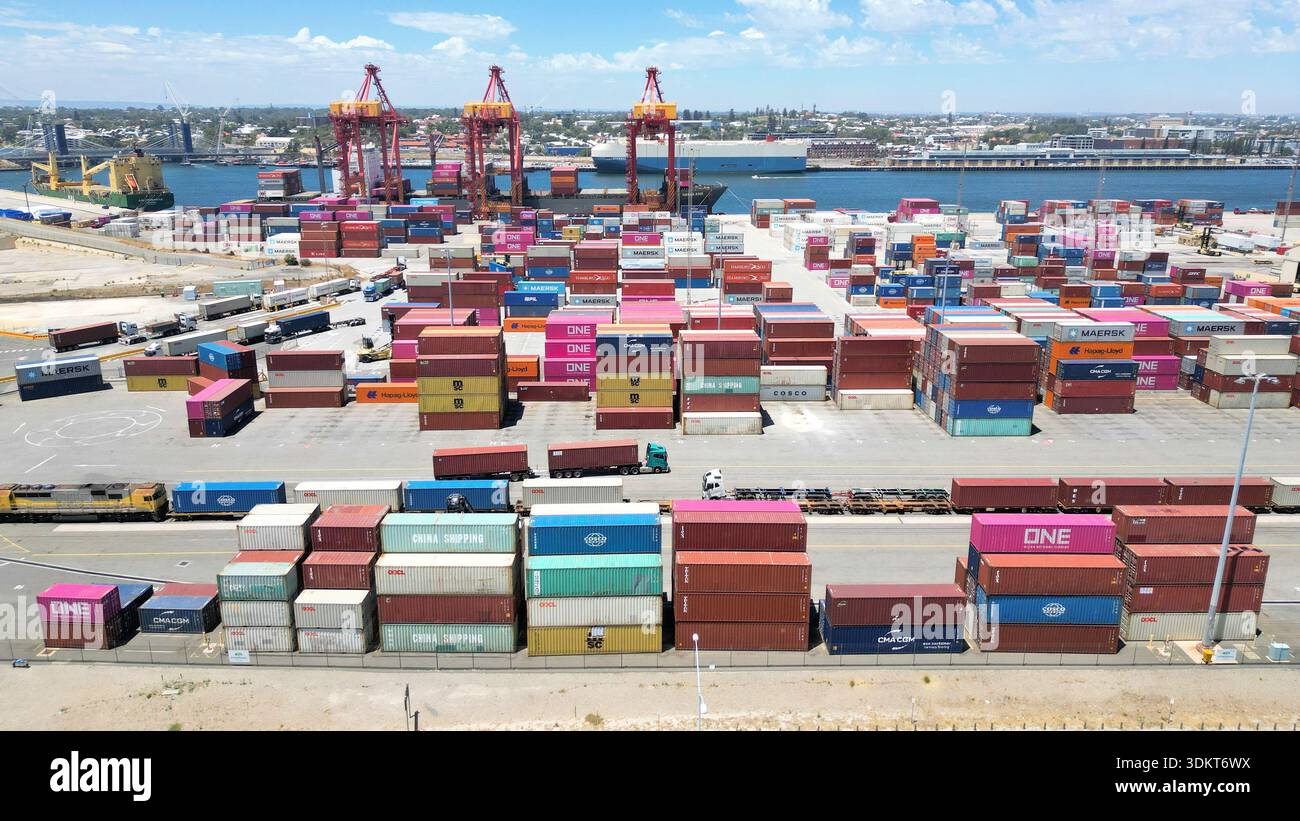 Container impilati e gru container scaricano una nave nel porto di Fremantle, mostrando le operazioni di movimentazione merci e l'infrastruttura logistica portuale. Foto Stock