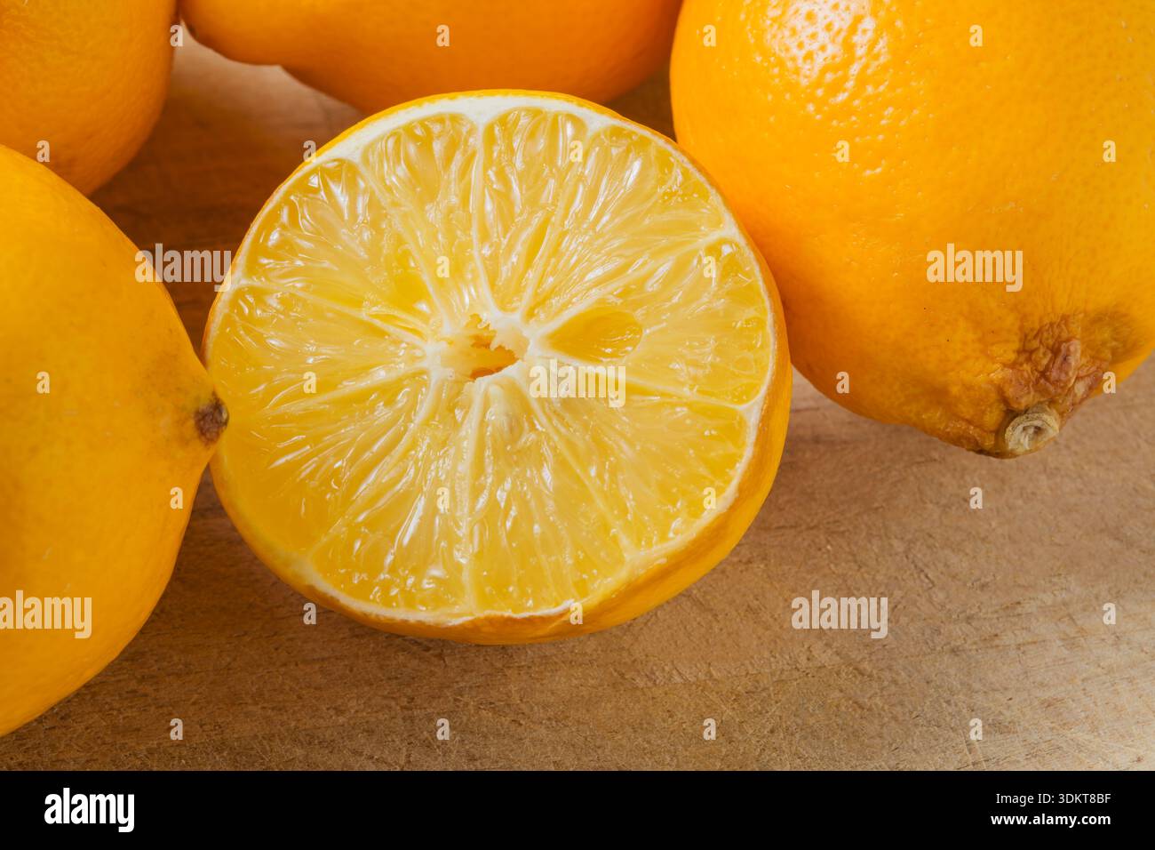 Un limone viene tagliato a metà e posto su un tavolo. Gli altri limoni sono interi e posti accanto al limone tagliato Foto Stock