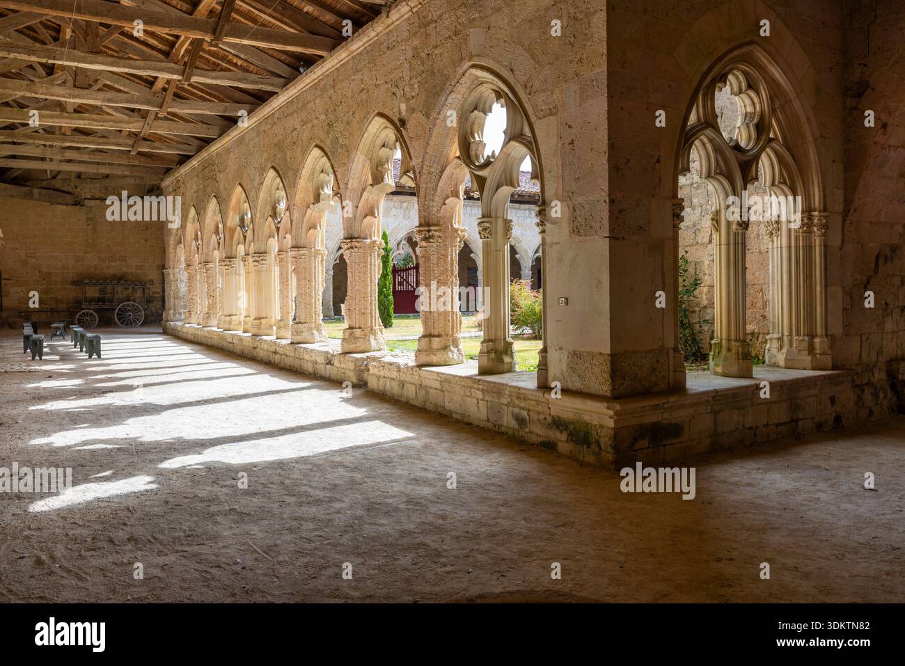 Antica galleria di pietra che crea motivi di luce e ombra sul terreno in un chiostro storico Foto Stock