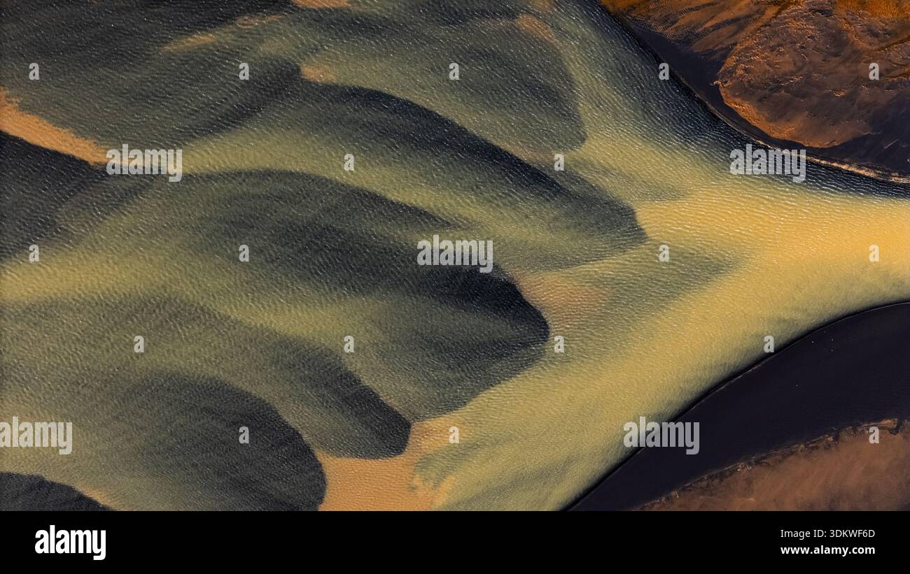 Vista aerea dei canali fluviali intrecciati che attraversano il paesaggio, creando un ipnotico arazzo di colori e texture contrastanti, Selfoss, Islanda. Foto Stock