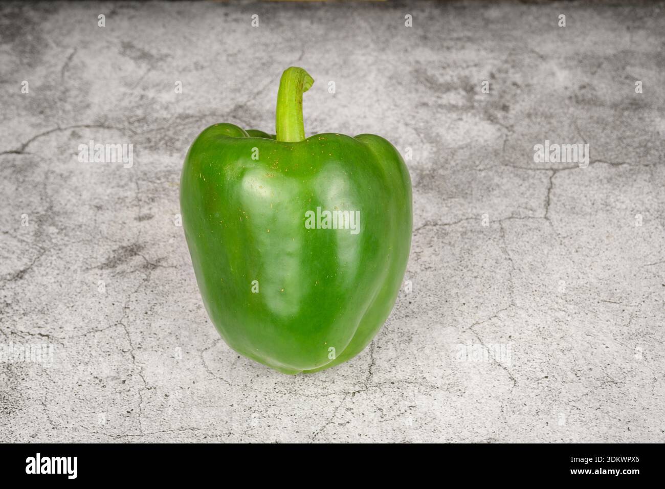 Peperone verde su sfondo grigio in calcestruzzo, durata minima con spazio di copia. Cibo sano e concetto primaverile. Foto Stock