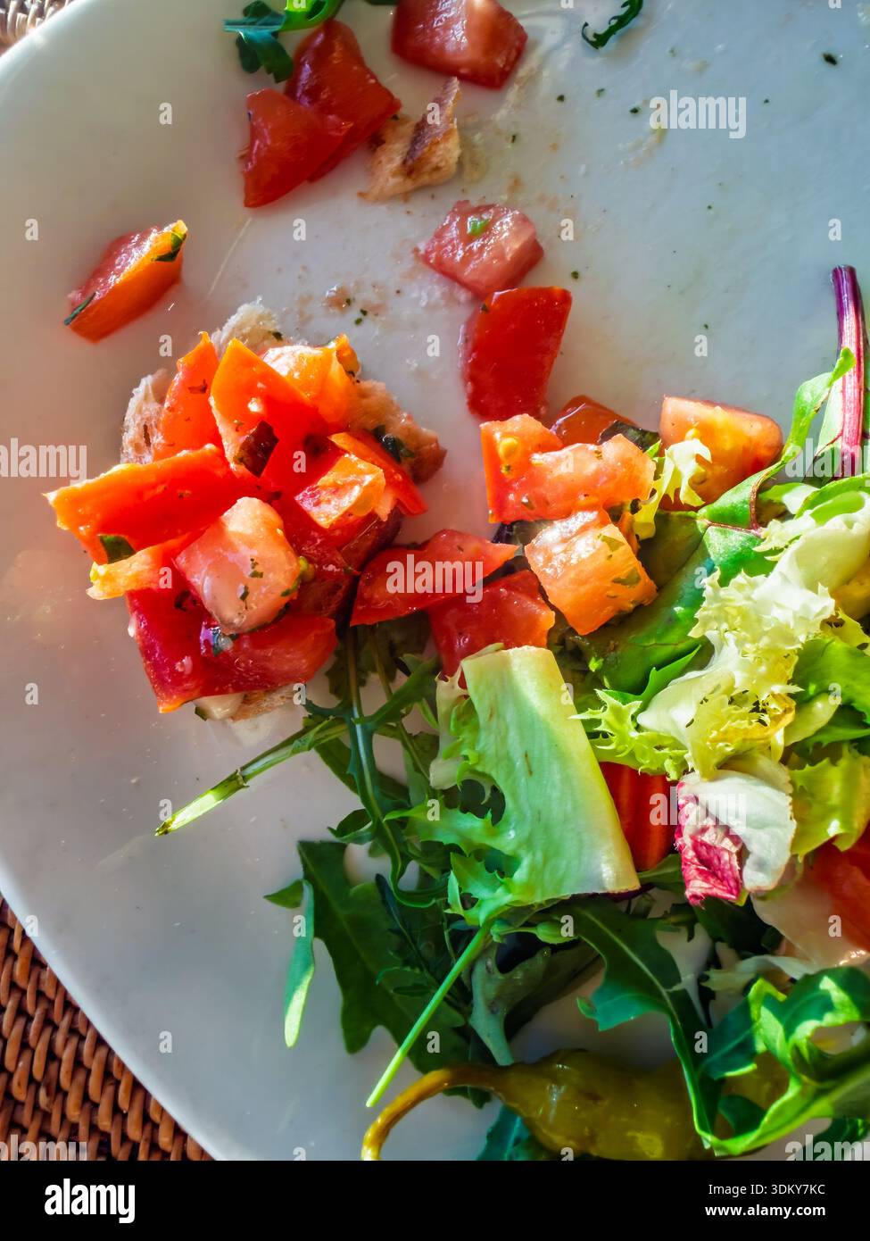 Vista dall'alto Di Un piatto con i resti di un'insalata fresca, con pomodori a dadini, peperoni, lattuga ed erbe aromatiche, per un'esperienza culinaria salutare Foto Stock